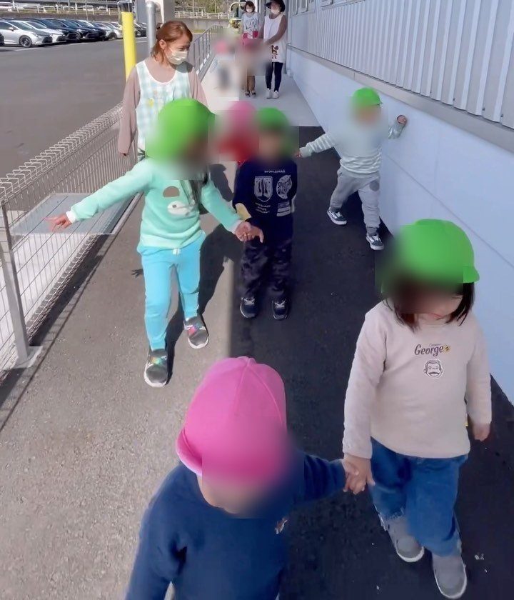 お散歩のようす（カラー帽子で並んで歩く園児たち）